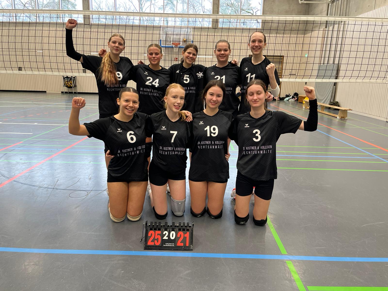 U18 Volleyballerinnen Mannschaftsbild vor dem Netz. 5 Mädels stehend, 4 kniend davor. Gnaz vorne Punktetafel mit Spielstand 25 zu 21.
