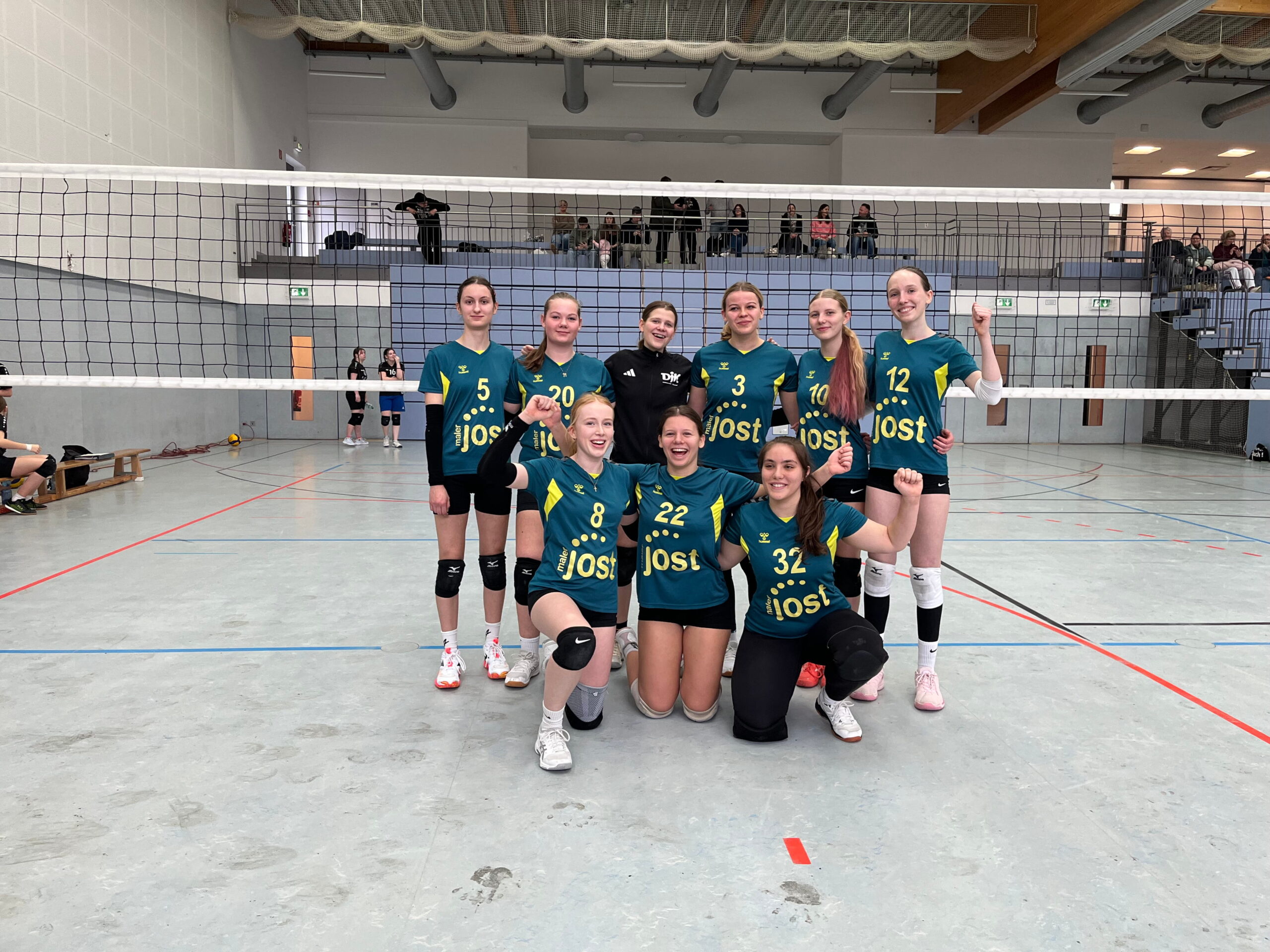 Gruppenbild U20 Volleyballerinnen auf dem Volleyballfeld in der Sporthalle.