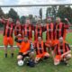 Gruppenbild DJK AH beim Turnier in Helmsheim. 9 Männer in Fußballtrikots vor Tor in siegreichen Gesten.