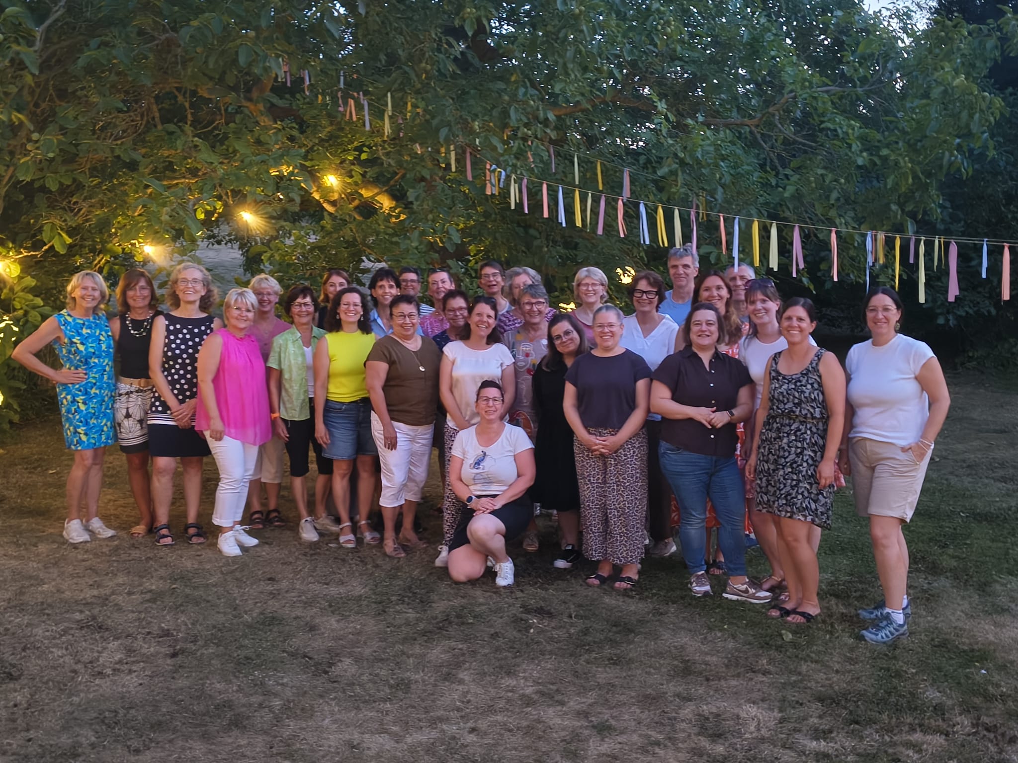 Gruppenbild Fitnessgruppen der DJK Bruchsal beim Sommerabschluss unter einem großen Baum mit Lichterketten und Fähnchen.